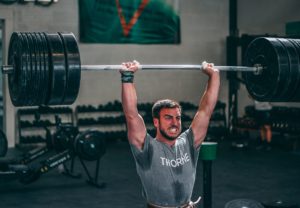 Grimacing male athlete holding a barbell with 315 pounds overhead.