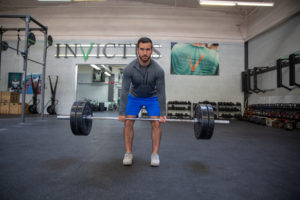 Male athlete facing the camera with the bar at his knees on a 225# deadlift.