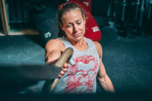 Female masters athlete doing single-arm ring rows.