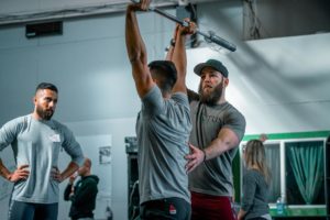 The Invictus weightlifting coach works with an athlete on his jerk overhead position.