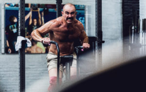 Grimacing male athlete going all out on Assault Bike sprints.