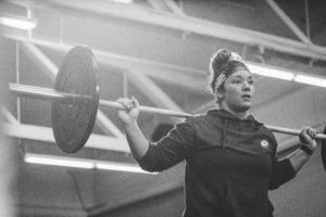 Female athlete with barbell on back preparing to do a snatch balance.