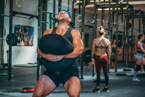 Male athlete doing a heavy sandbag squat.