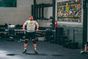 A male weightlifter doing a clean pull with 315#