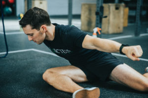 Male athlete doing an advanced version of pigeon pose.