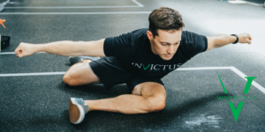 Male athlete doing a version of pigeon pose.