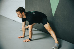 Male athlete does side split progression against the wall.